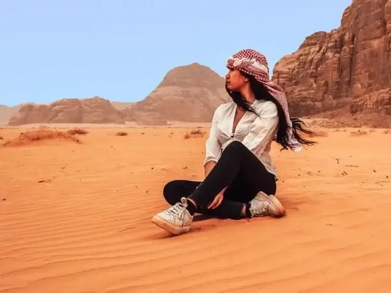 Female traveler sitting in the sand enjoying the desert view in Wadi Rum